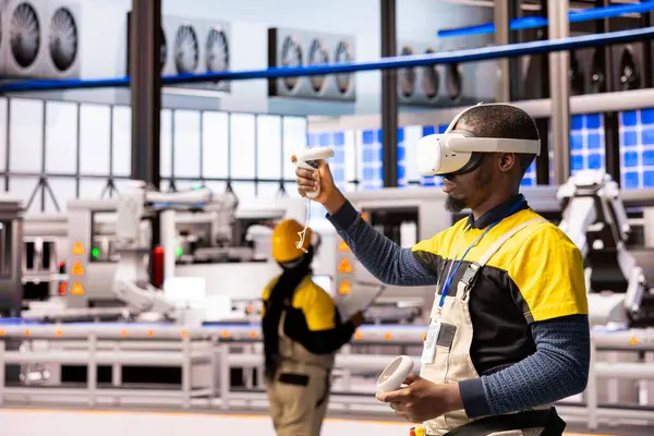 Otomatik fabrikadaki profesyonel mühendis, endüstriyel sanayi işletmeleri için yenilikçi yazılımı test etmek amacıyla VR kulaklık takıyor. Siyah erkek teknisyen sanayi 4.0 eğitimi için artırılmış gerçekliği kullanıyor..