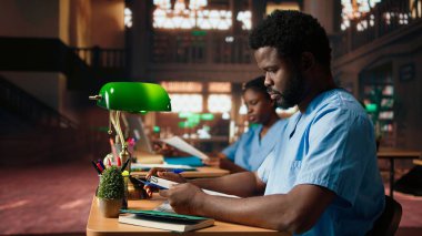 Afro-amerikan tıp öğrencisi tıp fakültesi kütüphanesinde farmakoloji öğreniyor. Tıp fakültesi, sağlık kariyeri için akademik eğitim. Kamera A.