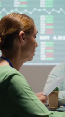 Şirketin hedeflerini yatırımcıların şirket ilerlemesi beklentileriyle aynı hizaya getirmek için projeksiyon ve diyagramlar kullanarak dosyaları ve performans göstergelerini değerlendiren dikey Video Çeşitli profesyoneller grubu