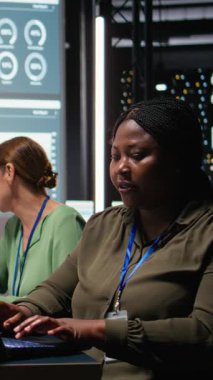 Afrikalı Amerikalı danışmanın dikey video portresi güncellemeleri gözden geçirmek, bir iş stratejisi oluşturmak ve net hedefler belirlemek için bir gece toplantısında dizüstü bilgisayar kullanıyor. Kadın şirket yöneticisi