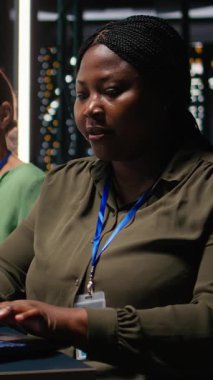 Dikey Video Afrikalı Amerikalı analist ve meslektaşları, küresel iş gelişimini kolaylaştırmak için dizüstü bilgisayardaki görüşleri gözden geçirip, yıllık veri raporlarını gece yapılan bir toplantıda inceliyorlar. Çalışma ekibi.