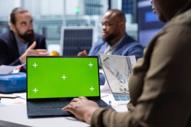 Endüstriyel bitki araştırma ve geliştirme departmanı yöneticisi model dizüstü bilgisayar kullanarak tesis geliştirme şemaları üzerinde çalışıyor. Fabrika uzmanı yeşil ekran not defteriyle taşıyıcı bant planları geliştiriyor