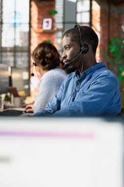 Ofisteki müşteri soruşturmaları, şikayetleri ve destek talepleriyle ilgilenen yardımcı bir çağrı merkezi temsilcisi. Afro-Amerikan müşteri hizmetleri temsilcisi müşterilere ürünlerle ilgili konularda yardımcı olur