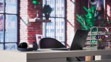 Minimalist boş bir masa içeren zarif, modern bir çatı katı dairesi. Parlak ferah ve şık, lüks ev ofisi şık mobilyaları ve açık tasarımı birleştirerek sofistike sakin bir ortam yaratıyor..