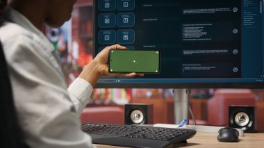 AI LLM sohbet robotu yazılımını takip etmek için izole ekran cep telefonu kullanan bir kadın. Afrikalı Amerikalı apartman dairesinde akıllı telefon ve bilgisayarında GPT programı kullanıyor.