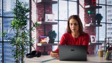 Gülümseyen bayan internet siparişini öderken kartını tutuyor. Ev ofisteki tabletle para aktarıyor ve alışveriş yapıyor. Kredi bakiyesini kontrol ettikten sonra memnun kadın alışverişi. Kamera B.