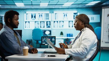 Afrika kökenli Amerikalı doktor ve hasta teşhis araçları, profesyonel bakım ve sağlıkla detaylı bir istişare içindeler. Doktor, genç bir adama hastalığın önlenmesi için tavsiyelerde bulunuyor. Kamera B.