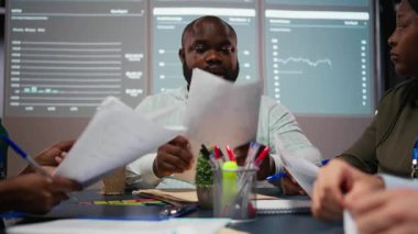 Arşivlenmiş dosyalardaki veri numaralarını değerlendiren, strateji odasında gece geç saatlerde net girişimcilik hedefleri belirlemek için raporları ve görüşleri paylaşan çeşitli uzmanları kapatın. Kamera A.