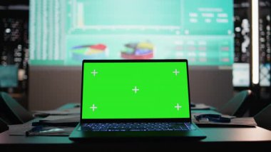 Boş toplantı odası, gece geç saatlerde öngörülen iş verileri ve çizelgeleriyle aydınlatılmış bir dizüstü bilgisayarı gösteriyor. Planlama ve tahminde bulunan karanlık ofis kurumsal ortamı.