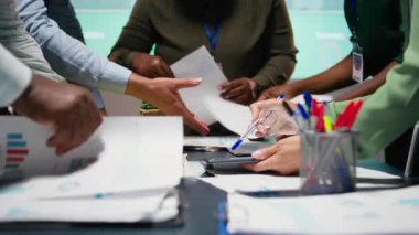 Geç saatlerde şirket brifinginde analizleri gözden geçiren çok ırklı bir ekip, modern ofis alanındaki beklentilerle iş hedeflerini aynı hizaya getirmek için tahminler ve veri içgörüleri. Kamera A.