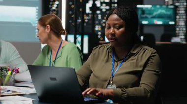 Afrikalı Amerikalı danışmanın portresi güncellemeleri gözden geçirmek, bir iş stratejisi oluşturmak ve net hedefler belirlemek için bir gece toplantısında dizüstü bilgisayar kullanıyor. Kadın şirket yöneticisi. Kamera B.