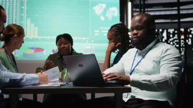 Siyahi şirket danışmanı hedefler için bir iş stratejisi oluşturuyor, pazar dinamiklerini ve gece geç saatlerde ofiste yapılan toplantılarda yapılan tahminleri inceliyor. Personel brifinge katıldı. Kamera A.