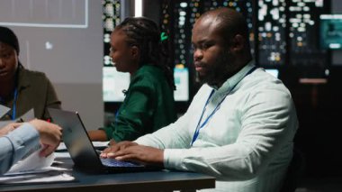 Toplantının geç saatlerinde sermaye fonu tahminleri sunan siyah denetçinin portresi ve iş haritaları üzerindeki veriler, bir kalkınma projesi için kaynak tahsisi. Brifing konferansı. Kamera B.