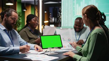 İş arkadaşları gece geç saatlerde fotokopi alanındaki raporları inceleyerek, eğilimleri analiz ederek ve görsel verilerle desteklenen stratejik güncellemeler üzerinde işbirliği yaparak çalışırlar. Analizli şirket projeksiyonları. Kamera A.