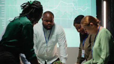 Çalışma saatleri dışında şirket brifinginde işbirliği yapan çeşitli personel grupları, modern bir şirkette iş hedeflerini yatırımcıların beklentileriyle aynı hizaya getirmek için projeler ve analizlerden yararlanıyorlar. Kamera B.