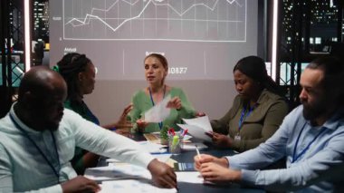 Çeşitli iş adamları toplantılarını saatler sonra görsel veri raporları için kapatın, bilgi grafikleri ve projeksiyonları gözden geçirirken finans hedefleri belirlemek için dosyaları paylaşın. İş istihbaratı. Kamera A.