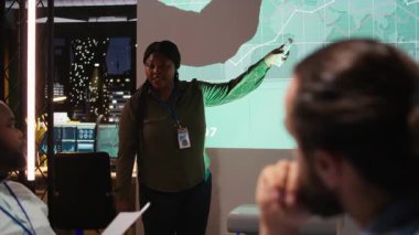 Çeşitli şirket ortakları proje zaman çizelgelerini ve gündemi inceler, konferans odasında saatler sonra kalkınma için bir strateji oluştururlar. İş ortamında hedef belirleme. Kamera A.