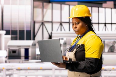 Profesyonel teknisyen, robotik kollar ve taşıma bantlarının yer aldığı üretim hattını analiz ediyor. Otomatik fabrika endüstriyel yenilikleri körüklemek için sanayi 4.0 sistemini ve akıllı imalatı kullanıyor.