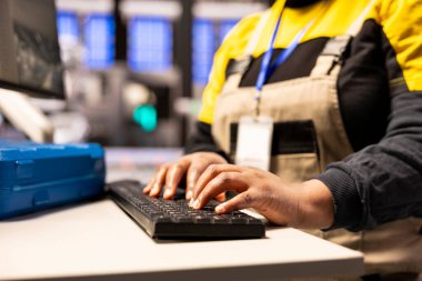 Fabrika mühendisi güneş enerjisi endüstriyel santralinde PC kullanarak üretim sürecini optimize ediyor. Afrika kökenli Amerikalı teknisyenin dijital yazılım aracılığıyla üretim performansını izlemesi.