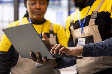 Otomatik fabrika uzmanları, güneş paneli üretiminde üretim akışını optimize etmek için sektör 4.0 yazılımını kullandılar. Dizüstü bilgisayardaki operasyonel verileri izleyen Afro-Amerikan teknisyenlere yakın çekim.