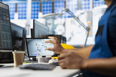 Siyah teknisyen güneş enerjisi üretim hattında optimizasyon geliştiriyor, masada tablet üzerinde çalışarak çevre dostu fotovoltaik sistemlere alternatif enerjiyi artırıyor. Sanayi Tesisi.