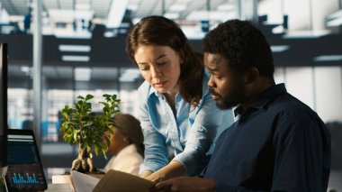 Ofisteki çalışanlar yönetimden proje evraklarını alıyor, yeni proje üzerinde çalışmaya başlıyorlar. İşçilere görev veren yönetici, gerekli doküman dizini, kamera A