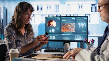 Kadın hasta için tüm ilaç ve malzemeleri hazırlayan kıdemli uzman, iyileşme için tedaviyi ve dozajı açıklıyor. İlaç ve ilaç reçetesi yazan bir doktor. Kamera A.