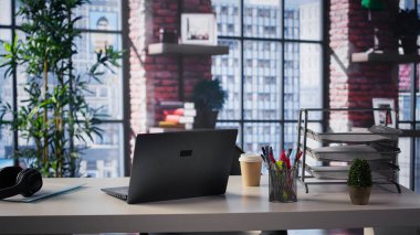 Boş bir masası olan lüks bir çatı katında lüks bir ofis. Gösterişli nötr tasarım ve sanatsal detaylar kaliteli ve yaratıcı bir çalışma alanı oluşturur..