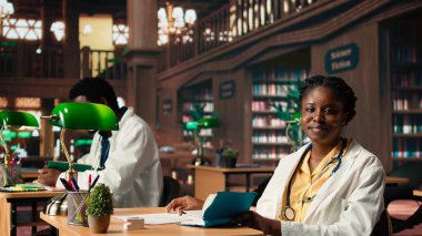 Odaklanmış tıp öğrencisi, önemli bir tıp fakültesi sınavına hazırlanarak farmakoloji üzerine bir ders kitabı okumayı seviyor. Üniversite kütüphanesindeki kadın öğrenci kariyeri için öğreniyor. Kamera A.