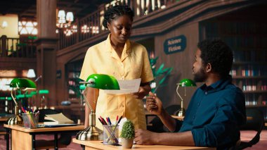 Afrika kökenli Amerikalı öğrenciler derslerini sessiz bir kampüs kütüphanesinde okuyorlar, akademik kaynak ve materyalleri eğitim gelişimine yardımcı olmak için kullanıyorlar. Çalışma zamanı. Kamera A.