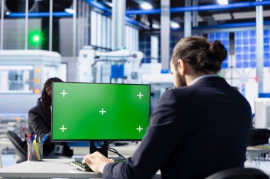 Güneş paneli fabrikasındaki teknisyen yeşil ekran bilgisayar yazılımıyla robot makine ayarlarını ayarlıyor. Fotovoltaik fabrikası çalışanı. Krom anahtar PC kullanarak vites performans sorunları teşhis ediyor.
