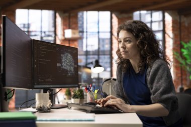 Yapay zeka sistemlerinde bakım yapan kadın bilişim mühendisi ofis masasında oturuyor. Genç kadın, makine öğrenimi için sibernetik ve algoritma geliştirici olarak çalışıyor..