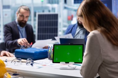 Yatırımcılar izole ekran cihazındaki ölçülere bakıyor, fabrika genişletme umutlarını araştırıyorlar. Üretim fabrikası yöneticileri, modelleme tabletindeki üretim verilerini analiz etmek üzere hissedarlarla bir araya geliyor.