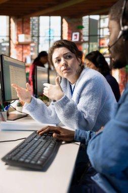 Müşteri hizmetleri müdürü CSM sistemindeki müşteri etkileşimlerini bilgisayarda denetliyor. PC 'de müşteri hizmetleri yönetim yazılımını kullanan çalışanı denetleyen çağrı merkezi yöneticisi