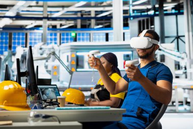 Siyah teknisyen, yenilenebilir enerji üretim endüstrisinde çalışmak için dijital yazılım kullanarak, VR kulaklık üzerinde çoklu güneş paneli tasarımlarını test ediyor. Erkek çalışan üretim hattını optimize ediyor.