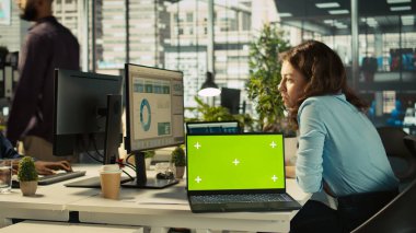 Ofis masasındaki yeşil ekran dizüstü bilgisayarda çalışan kurgu belgelerinin yanında. Veri tablolarını analiz eden, istatistiksel bilgileri yorumlayan, B kamerasının yanındaki defter.