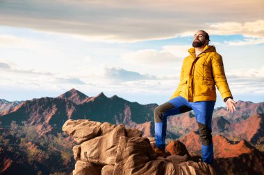 Sıcak giysili maceraperest, vahşi doğanın huzurunu, panoramik dağ manzarasını ve açık gökyüzünü sever. Rahatlamak için mükemmel bir ortam yaratır. Soğuk rüzgarlar yokuş yukarı.