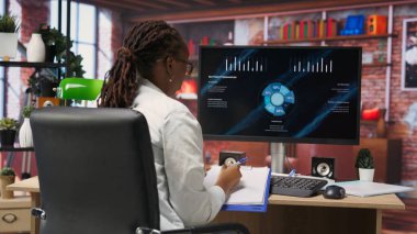 Kariyer gelişimi için faydalı finansal bilgiler edinmek amacıyla internet üzerinde akademik araştırma yapan öğrenci not alıyor. Çevrimiçi kurslara katılan Afrikalı Amerikalı bir kadın. Bilgi yazıyor. Kamera B.