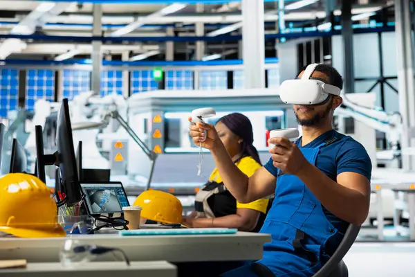 Siyah teknisyen, yenilenebilir enerji üretim endüstrisinde çalışmak için dijital yazılım kullanarak, VR kulaklık üzerinde çoklu güneş paneli tasarımlarını test ediyor. Erkek çalışan üretim hattını optimize ediyor.
