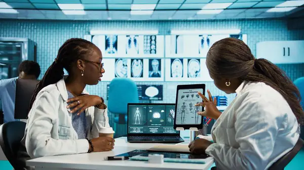 Klinik kontrolünde genç bir hastaya danışmanlık yapan bir sağlık uzmanı, radyoloji sonuçları ve tıbbi analiz ve tedavi stratejilerini güvence altına almak için teknolojik araçları birleştiriyor. Kamera B.