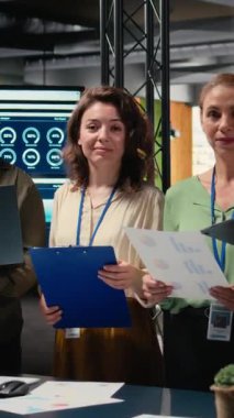 Çok uluslu bir şirket ofisinde rapor yazma ve strateji planlamasında işbirliği yapan çeşitli iş kadınlarının ortak zihniyetleri ve vizyonlarıyla güçlendirilmiş dikey video portresi. Kamera.