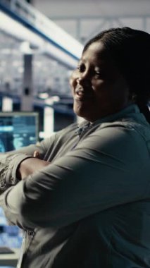 Gülümseyen veri merkezi yöneticisinin dikey video portresi yapay zeka donanımı işleme hızını ve verimliliğini geliştirmeye çalışıyor. Sunucu merkezindeki mutlu ekip lideri yapay zekayı desteklemek için ekipman yönetiyor.