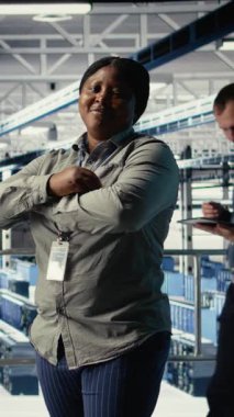 Gülümseyen veri merkezi yöneticisinin dikey video portresi yapay zeka donanımı işleme hızını ve verimliliğini geliştirmeye çalışıyor. Sunucu merkezindeki mutlu ekip lideri yapay zekayı desteklemek için ekipman yönetiyor.