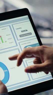Tablet ekranındaki altyapı grafiklerini kontrol eden veri merkezi çalışanının dikey videosu. Sistem sırasında veri tablolarını incelemek için sunucu odasındaki endüstriyel platformda bilişim uzmanı