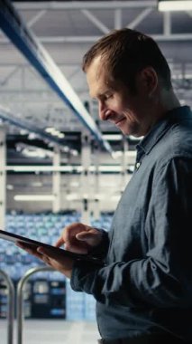 Dikey video Jolly IT uzmanı tesisteki tableti kullanarak sunucu odası aktivitesini izliyor. Happy Veri Merkezi teknisyeni, sistemlerin doğru çalıştığından emin olmak için testlerin sonuçlarını aygıtla gözden geçiriyor