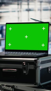 Veri merkezi programcılarının önünde yapay zeka donanımı işleme hızını artıran izole ekran laptopunun dikey görüntüsü. Sunucu merkezi çalışanları AI desteklemek için krom anahtar aygıtı kullanarak dişlileri yönetir