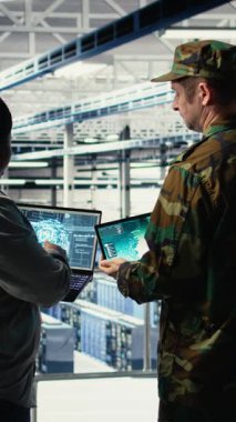 Veri merkezinde bulunan dikey video ordu komutanı ve yazılım geliştiricisi füze takibi için yapay zekayı radar sistemlerine entegre ediyor. Sunucu merkezinde hava hareketlerini analiz eden asker ve kadın programcı