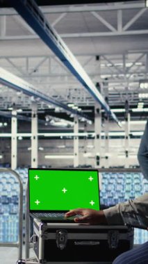 Dikey Veri Merkezi teknisyeni, yeşil ekran dizüstü bilgisayarla derin öğrenme sürecini gözlemler ve operasyonel ölçümleri gözden geçirir. Sinir ağları raporlarını gözden geçirmek için bu dizüstü bilgisayarı kullanan yönetici