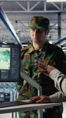 Veri merkezinde görev bölgelerini koordine eden dünya haritasına bakan askeri uzmanlardan oluşan dikey video ekibi. Sunucu merkezindeki ordu arkadaşları savaş alanını planlamak için küresel haritaya bakıyorlar