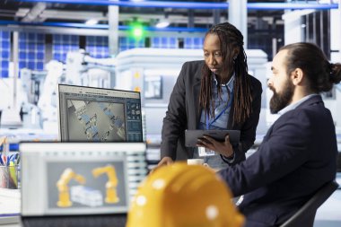 Güneş paneli çalışanları beyin fırtınası yapıyor, yazılımla robot makine ayarlarını ayarlıyorlar. Fotovoltaik fabrikası çalışanları ofiste tartışıyor, vites performans sorunları teşhis ediliyor